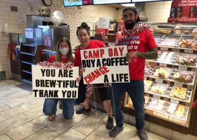 Three people holding camp day signs